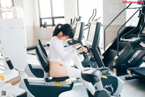 A woman is standing on a treadmill in a gym.