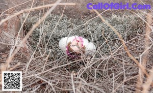 A naked woman sitting on a tree branch in the woods.