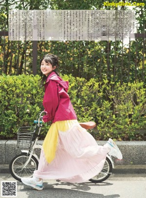 A woman in a red jacket and yellow skirt posing for a picture.
