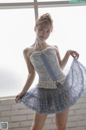 A woman in a blue corset is laying on a bed.