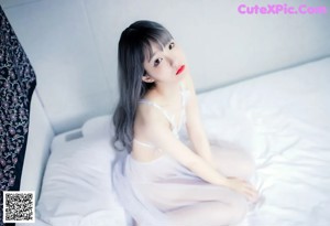 A woman in lingerie sitting on a bed.