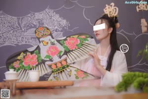 A woman in a pink dress standing in front of a table.