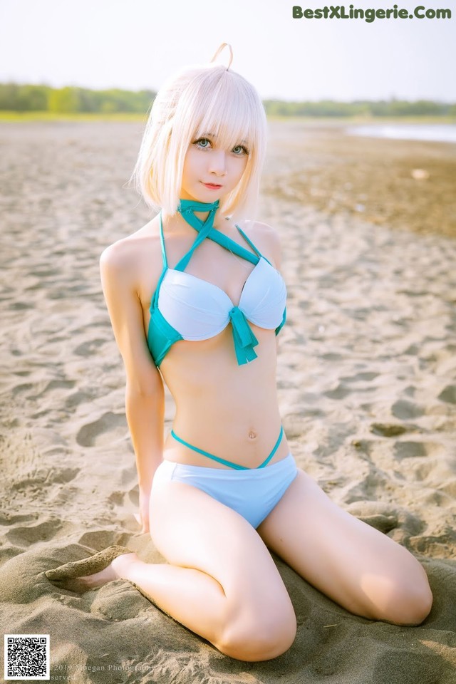 A woman in a blue bikini sitting on a beach.