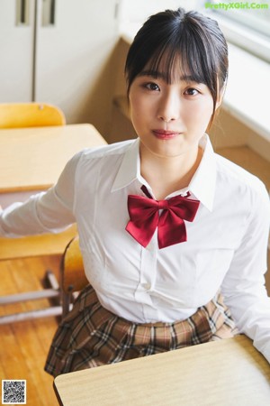 A woman in a school uniform sitting on a chair.