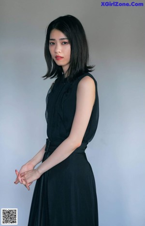 A woman leaning against a wall with her hand on her chin.