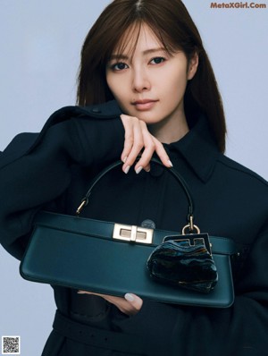 A woman in a brown sweater holding a red bag.