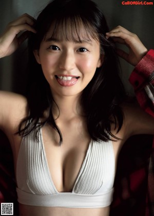 A woman in a blue bra sitting on a bed.
