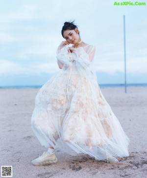 A woman in a white dress standing on a rock.