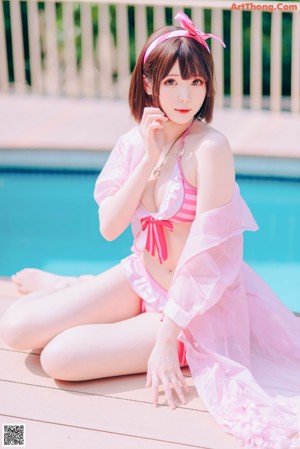 A woman in a pink bikini sitting on a wooden bench.