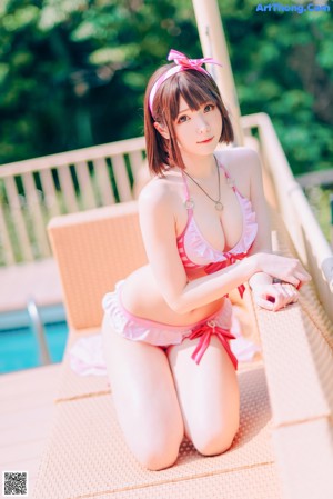 A woman in a pink bikini sitting by a pool.
