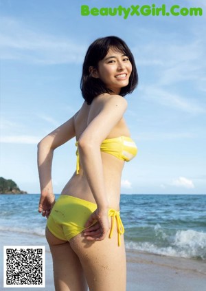 A woman in a yellow bikini holding a yellow flower.