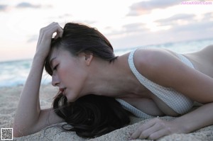 A woman laying on top of a bed next to a window.