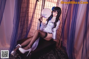 A woman in a white and blue dress holding a fan.