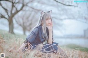 A woman in a blue dress sitting in the grass.