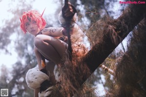 A woman with red hair holding a sword in a forest.