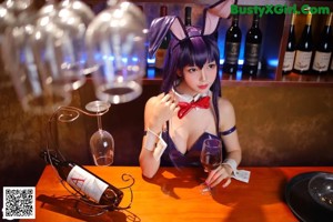 A woman in a bunny costume sitting at a bar.