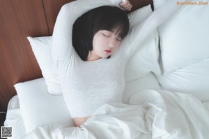 A woman sitting on a bed holding a cell phone.