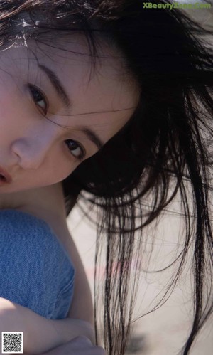 A woman laying on top of a bed covered in white sheets.