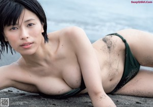 A woman in a white bikini sitting on a tiled floor.