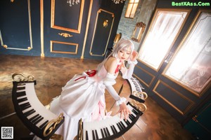 A woman in a white dress sitting on a white piano.