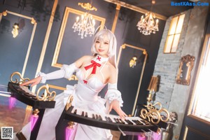 A woman in a white dress sitting on a white piano.