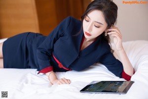 A woman is putting on her bare feet on a bed.